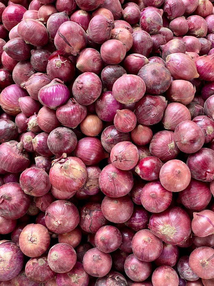 pexels-photo-12999831 A vibrant collection of fresh red onions in a vertical shot, perfect for culinary themes.