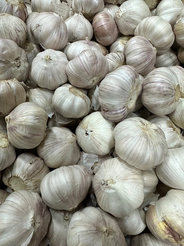 pexels-photo-19543592 A high-quality close-up image of fresh garlic bulbs stacked together, showcasing their texture and natural color.